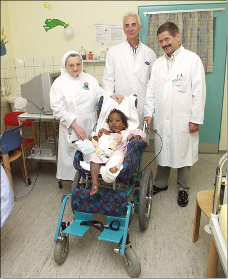 Stationsleitung Schwester Donatilla Seidenschwarz, Kinderchirurg Dr. Andreas Schmidt und Chefarzt Dr. Michael Heinrich mit Roselia, die ihr Bein nach der ersten Operation schon fast ausstrecken kann. &copy; KJF/Karg